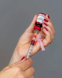 Hands drawing vitamin B-12 from a vial into a syringe